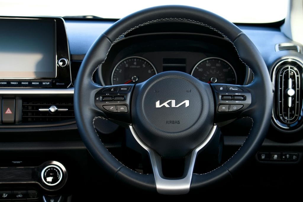 Primer plano del volante y el tablero de un Kia, en el que se aprecia el moderno diseño interior de los automóviles.